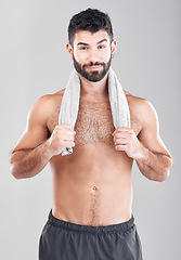 Image showing Health, fitness and man with towel on neck after sports workout, sweat and hygiene isolated on grey background. Portrait of coach, personal trainer and smile, body care mindset for exercise in studio