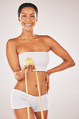 Image showing Health, tape measure and body with black woman and apple for nutrition and diet with fitness isolated on studio background. Portrait, smile and healthy lifestyle with weightloss and clean eating