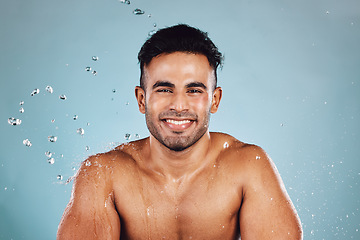 Image showing Water drops, portrait and skincare man isolated on blue background face cleaning, body shower and smile. Strong, beauty model or person facial glow in studio headshot washing and dermatology hygiene