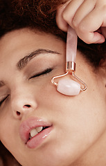 Image showing Skin care, face roller and woman doing massage in studio with dermatology and cosmetic tools. Aesthetic model with hands for spa facial product for health, wellness and natural skin youth glow