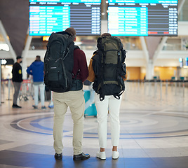 Image showing Couple, airport and reading on board, schedule and screen for flight on travel, plane or adventure with back. Man, woman and global immigration in lobby for airplane time, departure or transportation