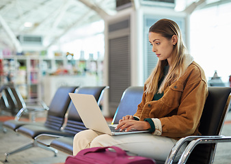 Image showing Airport, travel and woman typing on laptop in lobby, social media or internet browsing. Immigration, freelancer and female with computer for networking, web scrolling and waiting for flight departure