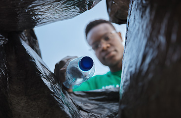 Image showing Recycle, bottle and black man with view in bag, sustainability and cleaning plastic pollution, earth day and community service. Saving the environment, charity and people putting trash in garbage bin