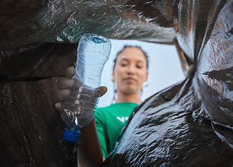 Image showing Recycle, bottle and black woman with view in bag, sustainability and cleaning plastic pollution, earth day and help in community. Saving the environment, charity and people putting trash in garbage.