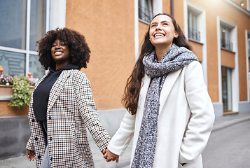 Image showing Woman, friends and holding hands walking in the city for friendship, travel or fun journey in the outdoors. Happy women taking walk or stroll touching hand with smile for sightseeing in an urban town