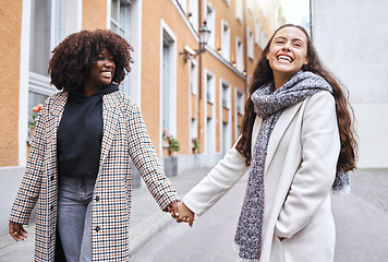 Image showing Woman, friends and holding hands with smile for travel, friendship or fun journey together in the city. Happy women walking touching hand and smiling for funny outdoor traveling in an urban town