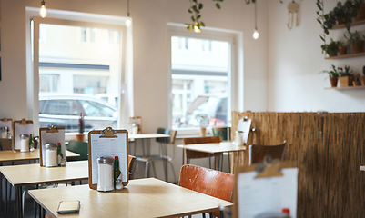 Image showing Table, chair and menu in an empty coffee shop in the city ready for service on opening day. Furniture, restaurant and decor on the interior of a small business cafe in the morning waiting to serve