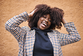 Image showing Black woman, laughing and afro for fashion, style or hair against a wall background. Portrait of happy African American female model touching stylish curls and smiling in happiness for haircare