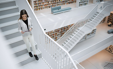 Image showing Top view, stairs and woman in library, tablet or online research for university, reading or education. Female, girl or student with device, bookshelves or search internet for knowledge or information