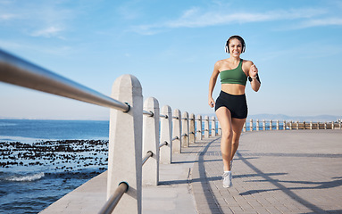 Image showing Running, music and woman at beach for fitness, exercise and morning cardio with energy in sports. Radio, podcast and workout run by girl at ocean for training, happy or relax with audio motivation