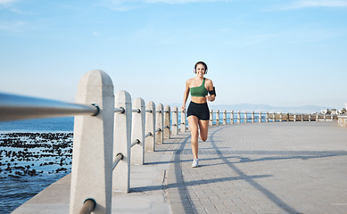 Image showing Fitness, woman and running by the beach side in Cape Town for cardio exercise, training or workout. Active female runner enjoying summer run or exercising for healthy wellness in the nature outdoors