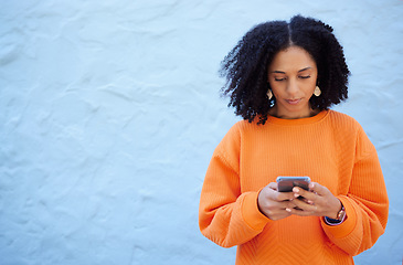 Image showing Black woman, cellphone and typing on blue background, wall or mockup. Female with mobile, technology and social media for reading notification, online advertising and website contact on 5g networking
