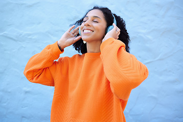 Image showing Black woman, headphones and music with smile by wall background on urban adventure, relax and freedom. African gen z girl, streaming audio and quality sound on app, web or internet with peace in city