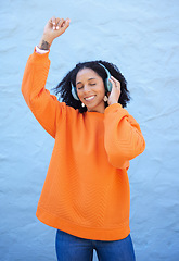 Image showing Black woman, headphones and music for dance by wall background on urban adventure, relax or freedom. African gen z girl, streaming audio or quality sound on radio, web or internet for dancing in city