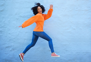 Image showing Happy, excited and woman jumping by a wall while walking in the city on a vacation or weekend trip. Happiness, smile and young lady from Mexico with energy, freedom or adventure in town on a holiday.