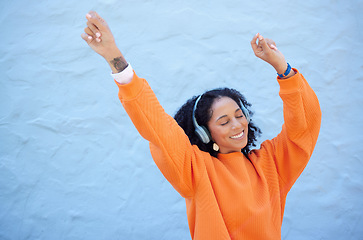 Image showing Black woman, hands up or dancing to headphones music on isolated blue background, fashion mockup or wall mock up. Smile, happy or dancer student listening to radio, audio or energy podcast in freedom