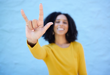 Image showing Rock sign, fashion and hands of black woman on blue background with smile, happy mindset and peace. Hand gesture, beauty and face of African girl relax with urban style, trendy and stylish clothes