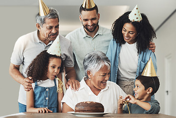 Image showing Happy birthday, senior woman and family celebration at a table with a cake, love and care in a house. Children, parents and grandparents together for a party to celebrate excited grandma with dessert