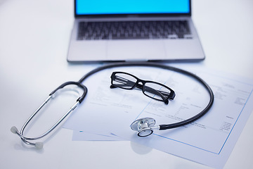 Image showing Laptop, stethoscope and medical documents in a office for research, diagnosis or test results. Computer, technology and glasses on a desk for doctor to read healthcare paperwork in hospital or clinic