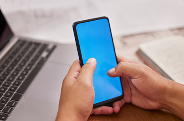 Image showing Person, hands and phone with green screen on mockup by laptop for advertising, marketing or communication at office desk. Hand of employee on mobile smartphone display or chromakey for advertisement