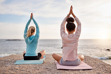 Image showing Yoga, back and arms raised on sunrise beach, ocean or sea for morning meditation, chakra balance and bonding. Yogi, women and relax friends on nature rock for zen, healthcare wellness or spirituality