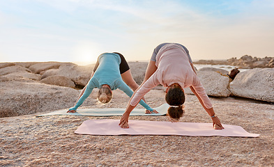 Image showing Women, yoga or stretching on beach mat for relax training, workout or exercise for healthcare wellness, muscle relief or flexibility. Friends, yogi or pilates people on rock for zen fitness at sunset