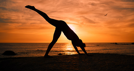 Image showing Fitness, yoga and silhouette of woman at sunrise on beach for exercise, training and pilates workout. Morning, meditation and shadow of girl balance by ocean for sports, wellness and stretching legs