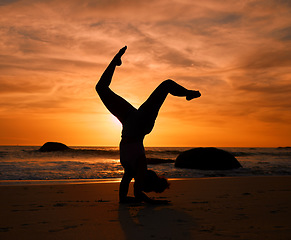 Image showing Yoga, silhouette or handstand pose on sunset beach, ocean or sea in evening workout or relax exercise training. Yogi, woman or sand balance at sunrise for healthcare wellness fitness or strong body