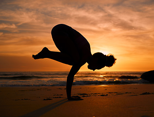 Image showing Yoga, silhouette or crows pose on sunset beach, ocean or sea for evening exercise, workout or relax training. Yogi, woman or balance on sand at sunrise for fitness, healthcare wellness or strong body