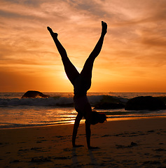 Image showing Yoga woman, silhouette or handstand on sunset beach, sea or ocean in workout or relax exercise training. Yogi, pilates or sand balance pose at sunrise for healthcare wellness fitness or strong body