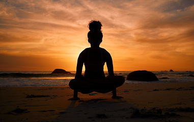 Image showing Sunset, yoga and silhouette of a woman on the beach in a lotus pose doing a meditation exercise by the sea. Peace, zen and shadow of a calm female doing a pilates workout outdoor at dusk by the ocean