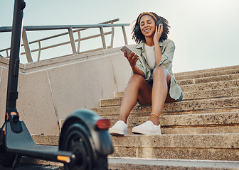 Image showing Black woman outdoor, smartphone and headphones with scooter, music and travel with 5g network for audio streaming in city. Sustainable transportation, listen to audio or podcast and relax on steps