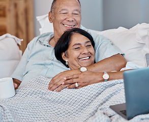 Image showing Elderly couple streaming a movie on a laptop while relaxing on a sofa in their living room. Love, home and happy senior man and woman in retirement watching a video on computer together on a couch.