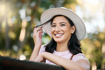 Image showing Woman, park and portrait of a female traveler on a garden bench with a smile from travel. Freedom, happiness and hair twirl of a Asian person on holiday feeling happy on vacation enjoying nature