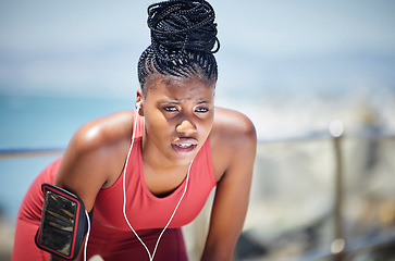 Image showing Tired, running and black woman with runner fatigue by the ocean for workout, exercise and fitness. Summer, sweating and marathon run of a athlete on a sprinter break by the sea with rest from sport