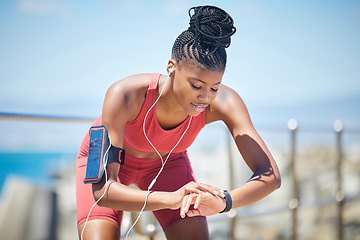 Image showing Fitness, smartwatch and runner time of a black woman by the sea doing exercise and running workout. Outdoor, run tracker app and mobile of a athlete with headphones by the ocean listening to audio