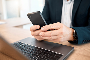 Image showing Hands, phone and research with a business man typing a text message while working on his laptop. Mobile, communication and networking with a male manager or employee reading an email at work