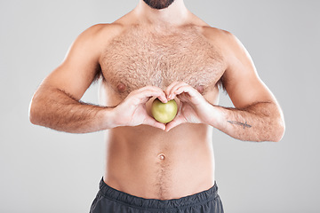 Image showing Man, fitness and heart hands with apple in studio isolated on a gray background. Food, wellness and male model with love hand gesture, fruits for nutrition or healthy diet, vitamin c or minerals.