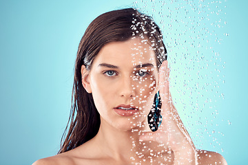 Image showing Face, water splash and skincare of woman in shower in studio isolated on a blue background. Beauty, portrait and young female model washing, cleaning or bathing for hygiene, wellness and health.