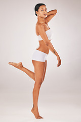 Image showing Portrait, body and balance with a model black woman in studio on a gray background for natural beauty. Fitness, wellness and underwear with an attractive young female posing to promote health