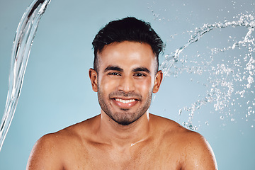 Image showing Water splash, portrait and beauty man isolated on blue background face cleaning, body shower and smile. Happy, skincare model or person facial glow in studio headshot washing and dermatology hygiene