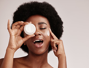 Image showing Skincare, beauty and black woman holding cream on face, afro and excited advertising luxury skin product promotion. Dermatology, spa cosmetics and facial for happy model isolated on studio background