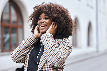 Image showing Black woman, earphones and listening to music in the city streets with smile for entertainment. Happy African American female walking in a urban town smiling in joyful happiness for audio sound track