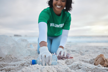 Image showing Hand, bottle and a volunteer woman on the beach for community, charity or activism during a clean up. Cleaning, environment and plastic with a female picking up plastic litter or polution on a coast