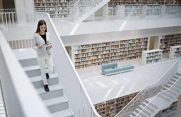 Image showing Walking student, tablet or woman in library for social media, education or learning. Bookshelf, books or girl on tech for scholarship networking, search or planning school project at collage campus