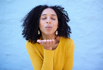 Image showing Black woman blowing kiss in air for love, care and flirting on blue background, wall backdrop or outdoor. Young girl, hand kisses and expression of happiness, romance and kissing face emoji with lips