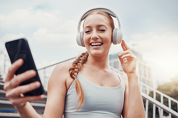 Image showing Fitness, woman and phone with headphones in the city for music listening, 5G connection or workout motivation. Happy female runner smile for headset, smartphone or audio track for exercise on stairs