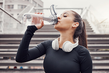 Image showing Workout, hydration and a sports woman drinking water outdoor in the city during cardio or endurance exercise. Runner, fitness and hydrated with a female athlete training in an urban town for health