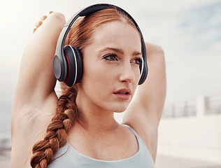 Image showing Stretching, fitness and face of woman with headphones listening to music, podcast and audio for warm up. Running, sports and girl start workout, wellness exercise and marathon training in urban city