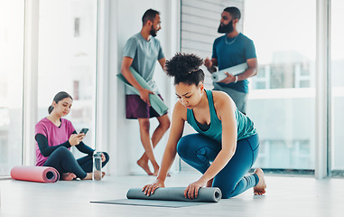 Image showing Yoga, fitness and a black woman rolling her mat on the floor of a studio for exercise or wellness. Gym, workout and health with a female yogi in the gym for pilates training or spiritual wellbeing